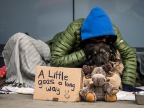 A homeless person kisses her dog while laying on Toronto’s Dundas Street West. Postmedia