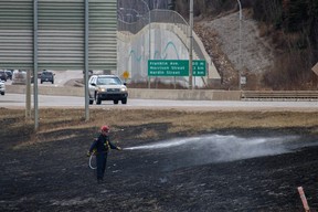 A firefighter with the Fort McMurray Fire Department sprays water onto the site of a controlled burn near Highway 63 on April 27, 2023. The controlled burns are part of the RMWB's FireSmart program, which is designed to fight and prevent fires and wildfires in the region. Vincent McDermott/Fort McMurray Today/Postmedia Network