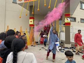 A man throws coloured chalk powder into the air outside the Sanatan Mandir Cultural Society in Fort McMurray to celebrate the opening of Fort McMurray's first Hindu temple on May 22, 2023. Vincent McDermott/Fort McMurray Today/Postmedia Network