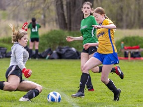 Sophie Langdon of the BCI Mustangs gets the ball past St. John's Eagles goalkeeper Cassia DiFelice to score a goal during an AABHN high school girls soccer match on Wednesday May 3, 2023 at John Wright Field in Brantford, Ontario. Brian Thompson/Brantford Expositor/Postmedia Network