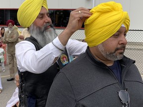 Cheema Amrit, left, a member of the Sikh Motorcycle Club, winds a bright yellow turban around the head of Mohan Chohan at the annual Khalsa Day celebrations on Park Road North in Brantford on Sunday, May 14. SUSAN GAMBLE/BRANTFORD EXPOSITOR