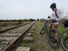 Mike Sewell points to a segment of the disused CN Rail line that crosses Highway 401 in Greater Napanee on April 28, 2023. Council is considering whether it should sell the property to an interested buyer or follow up on community members' requests to look at potentially developing the property as a multi-use trail, which could connect into the Cataraqui Trail system.