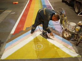 Jessy Mathers of Pavement Pros paints a progress pride flag on a crosswalk at the intersection of Ontario and Clarence streets in Kingston, Ont. on Wednesday, May 31, 2023