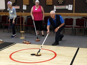 Allan Wilhelms of Mayerthorpe aimed for the house while Barrhead player Mary Baron, behind him, observed during the Alberta Floor Curling Association tournament. The Mayerthorpe Legion hosted the tournament on May 4, which saw more than 70 seniors participating. Wilhelms' team took third place.