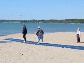 Visitors take a stroll on Wednesday on a plastic runway installed along a section of the Walker Street beach in Port Dover that belongs to Norfolk County.  The runway provides people in wheelchairs and other assistive devices with access to the waterfront.