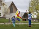 Two children wave at vehicles while holding a Pride flag across the road from the Netherlands Reformed Congregation church in Norwich, Ont., on Wednesday, May 3, 2023. The southern Ontario township voted last month to prohibit Pride flags on municipal property.