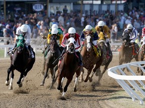 Manitoba Derby winner Oil Money (centre), with Orlando Mojica, has the lead at the first turn at Assiniboia Downs on Mon., Aug. 5, 2019.