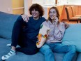 Young couple watching TV, eating snacks after smoking marijuana.