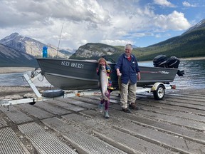Olivia Moorhouse poses beside her grandpa, Kit Pye, both holding fish they caught at Spray Lake Reservoir. Photo by Corey Moorhouse.
