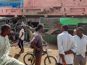 People walk past a medical centre building riddled with bullet holes at the Souk Sitta (Market Six) in the south of Khartoum on June 1.