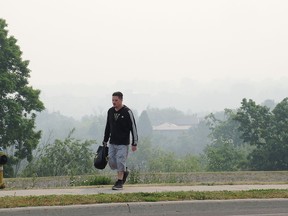 A man walks up Centennial Drive as smoke from wild fires in Quebec and Ontario filled the sky