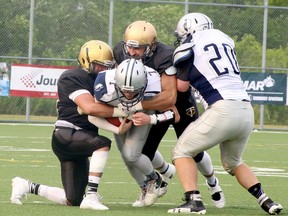 Sudbury Spartans quarterback Nick Rideout (7) is tackled by a couple of Tri-City Outlaws while rushing the ball during Northern Football Conference action at James Jeome Sports Complex in Sudbury, Ontario on Saturday, July 15, 2023.