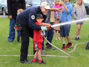 Mayerthorpe Fire Chief Randy Schroeder helped Jude Laboucane aim the fire hose during Canada Day events.