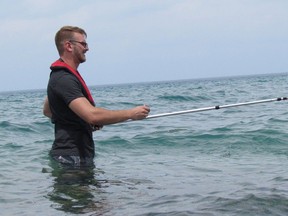 Mitchel Bortolon, a student public health inspector, is shown in this 2018 file photo taking a water sample from Lake Huron at Canatara Beach as part of Lambton Public Health's beach water sampling program. File photo/Postmedia Network