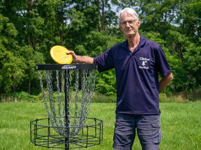 Rob Brown stands next to a disc golf basket.