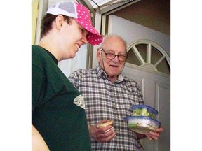 A young man handing an older man food in tupperware