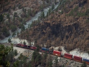 A Canadian Pacific freight train travels on tracks covered with fire retardant in an area burned by wildfire above the Thompson River near Lytton, B.C., on Sunday, August 15, 2021.