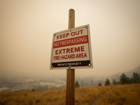 A warning sign about fire risk is seen as smoke from wildfires fills the air in Kelowna, B.C., on Saturday, Aug. 19, 2023.