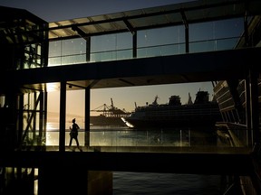 A woman is silhouetted on a walkway with a cruise ship and gantry cranes in the distance on Monday, Aug. 14, 2023. Multiple temperature records were set in B.C. and B.C. Hydro reported an electricity demand record that evening.