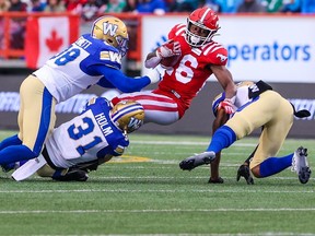 Calgary Stampeders running back Dedrick Mills is tackled by the Winnipeg Blue Bombers' Anthony Bennett and Evan Holm during CFL action at McMahon Stadium in Calgary on Friday, August 18, 2023.