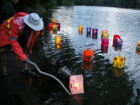 A woman nudges lanterns at the shore of Lake Pinafore