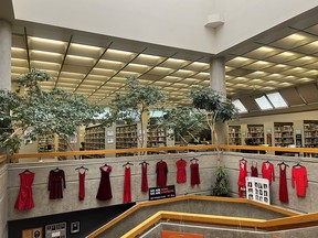 Red dresses hanging from a railing of a second floor