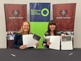 Two people seated at a table holding up pieces of paper.