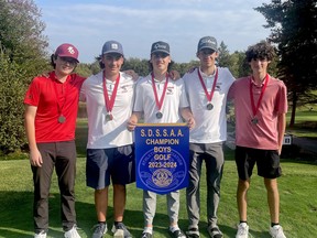 St. Charles College boys golf team members celebrate with their championship banner