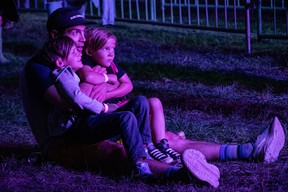 A man with his children watch the supergroup Trans-Canada Highwaymen perform at Wood Buffalo Ribfest in Fort McMurray on August 31, 2023. Vincent McDermott/Fort McMurray Today/Postmedia Network