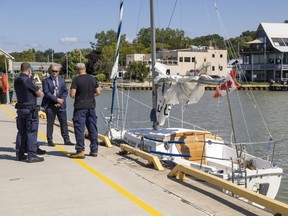 A witness talks to an OPP detective and two Canadian Border Services Agency officers near an abandoned sailboat tied off just south of the lift bridge in Port Stanley harbor on Fri.  Sept. 1, 2023. The keys were still in the vessel that arrived Aug.  25 and was reported to Elgin OPP five days later, (Mike Hensen/The London Free Press)