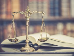 Stock photo of scales of justice in front of a book and shelves.