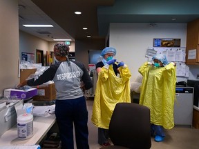 ICU health-care workers don protective gear before entering a room to care for a COVID-19 patient on a ventilator at the Humber River Hospital during the pandemic in 2020.