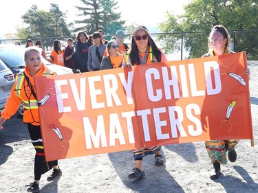 marchers walk with a banner that says "every child matters"