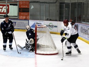 Darcy Horidchuk of the Stuckless team took the puck behind the net of the McSorely team, guarded by goalie Steven Hiemstra during the Hockey Heroes alumni hockey game