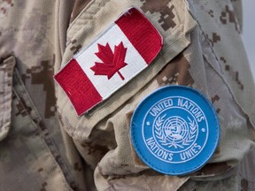 Canadian and UN flags are seen on the sleeve of a Canadian soldier, boarding a plane at CFB Trenton. THE CANADIAN PRESS/Lars Hagberg