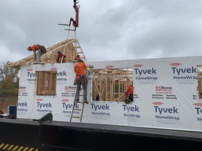 A crane lifts roof trusses into place on a home being constructed in a three-day blitz on Oneida Nation of the Thames on Friday, Oct. 20, 2023. Imagine Build is an organization working alongside Oneida Nation of the Thames to build homes in the community southwest of London.  (Brian Williams/The London Free Press)