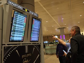 Passengers look at a departure board at Ben Gurion Airport near Tel Aviv, Israel, on October 7, 2023, as flights are cancelled because of the Hamas surprise attacks.