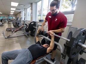 Eric Seed, manager of the Bob Hayward YMCA on Hamilton Road in London, helps member Gary Sage with a bench press on Thursday, Oct. 26, 2023. (Mike Hensen/The London Free Press)