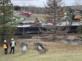 Work crews are shown at a main sewer line break in Cochrane, Alta. on Sunday Oct. 22, 2023.