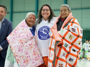 Vanessa Genier, founder and CEO of Quilts for Survivors, presents quilts to two elders and residential school survivors, Nokomis Julie Ozawagosh and Gert Nootchtai of Atikameksheng Anishnawbek, while Greater Sudbury Cubs Indigenous community relations leader Dominic Fletcher looks on during a pre-game ceremony before an NOJHL game between the Cubs and the Espanola Paper Kings at Gerry McCrory Countryside Sports Complex in Sudbury, Ontario on Thursday, October 12, 2023.