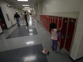 A student sorts through her locker in the school hallway in this Postmedia file photo.