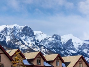 Rows of houses in the Canadian Rockies of Canmore, Alberta, with spectacular view of Rundle Mountain in the background.