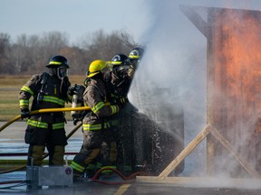 Firefighters spray a flaming propane cylinder.