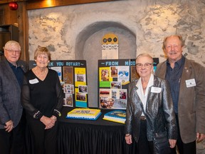Rotarians stand in front of a display of photos.