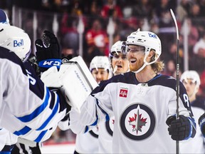 Kyle Connor of the Winnipeg Jets celebrates with the bench after scoring against the Flames during the first period of an NHL game at Scotiabank Saddledome on Oct. 11, 2023 in Calgary.