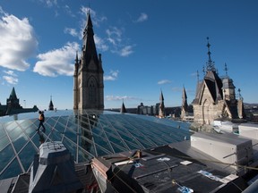 A worker walks over West Block’s glass roof. The federal New Democrats are planning to vote on Monday in favour of a Conservative motion to exempt all home heating fuels from the federal carbon tax.