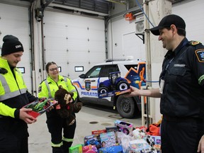 Paramedics Owen Thomas, left and Jessica Dionne, centre, along with Derrick Cremin, Emergency Management Services commander, right, check out some of the toys received