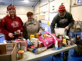 Chantal Zorad, on the left, Special Events Manager for the Norfolk County Fair and Horse Show, and Aaron Culver, on the right, Facilities Manager for the Norfolk County Fair, help pack up food for Donna Thompson, coordinator of the Waterford & District Food Cupboard during the annual Holiday Food Drive at the CIBC Aud Tuesday in Simcoe. CHRIS ABBOTT