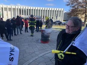In this file photo, a union supporter protests the Tory government's decision to disregard their signed collective agreements on pensions, as firefighter douse flames in a burn barrel on the legislature grounds.