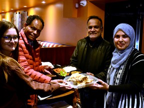 The Multicultural Association of Perth-Huron has partnered with two local restaurants to cook and deliver fresh, hot meals to Stratford's homeless and others in need this Saturday. Pictured from left are association volunteer Yulia Suliatytska, association executive director Geza Wordofa and Raja Find Indian Cuisine co-owners Zafar Quazi and Moury Tania with one of the meals they will be cooking up for those in need.